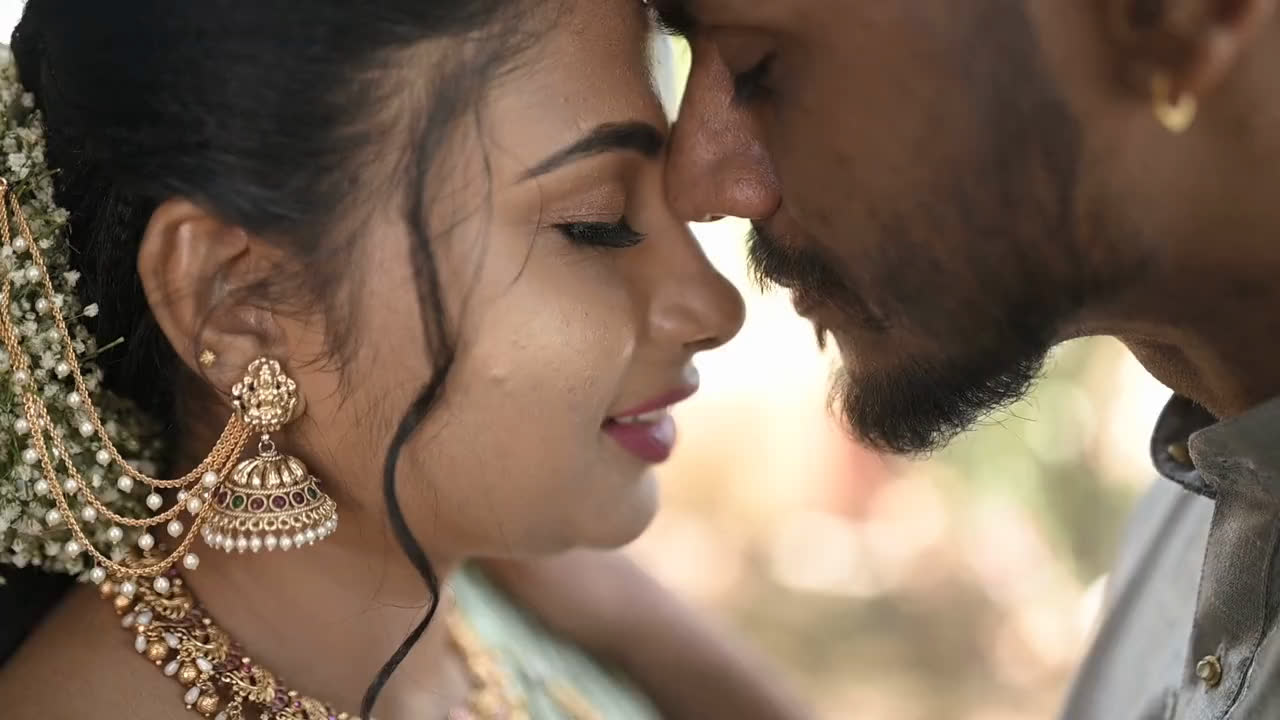 A bride and groom, foreheads touching, in soft light