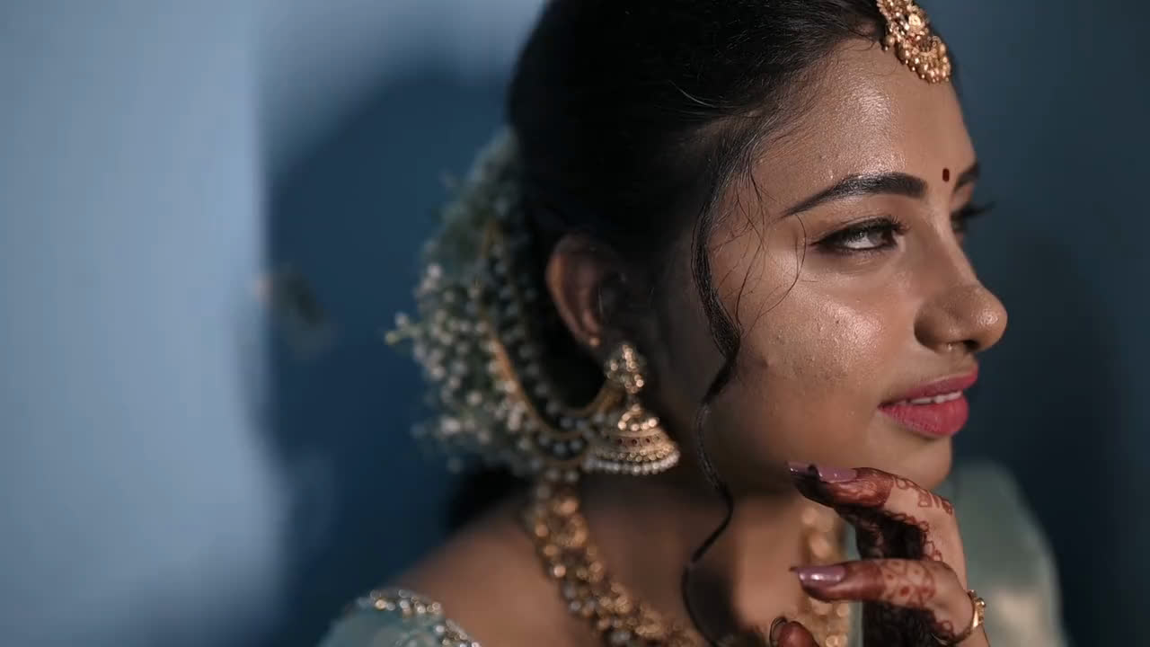 A South Indian bride in jasmine and gold jewellery, smiling to herself