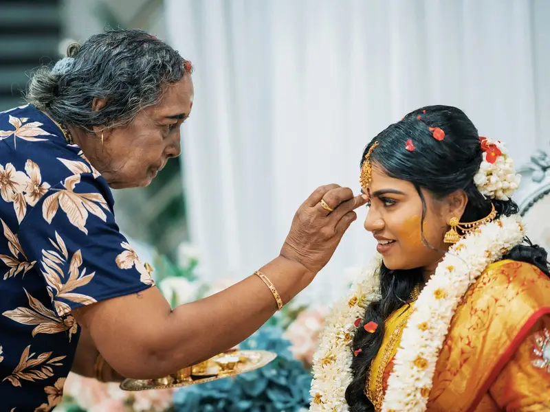 A grandmother blessing a smiling bride (tilak).