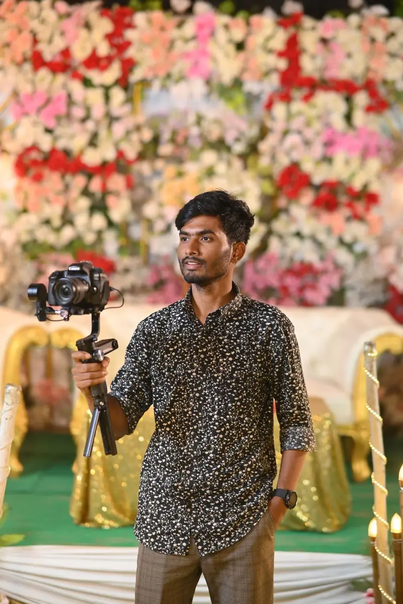 A videographer holding a camera on a gimbal at a floral wedding stage