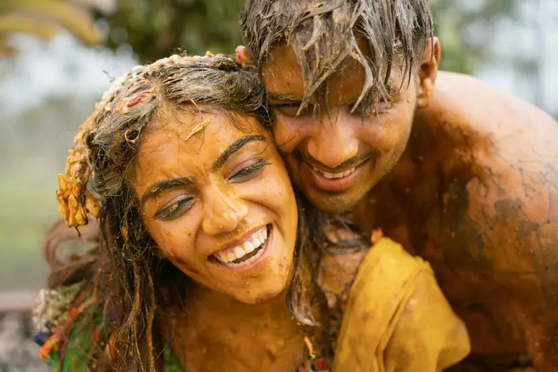 A couple covered in turmeric, laughing (haldi / mangala snanam).