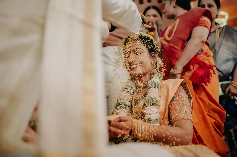 Bride laughing as rice flies, family around; warm.