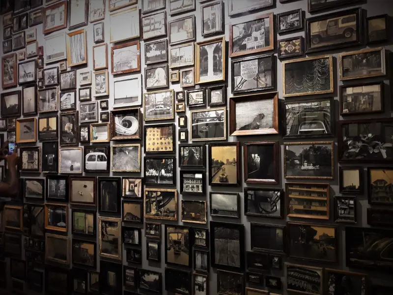 a wall crowded with framed photographs in dim light