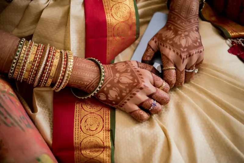 Mehendi hands resting on gold silk.