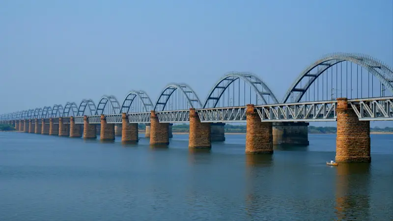A wide river with a long arch bridge.