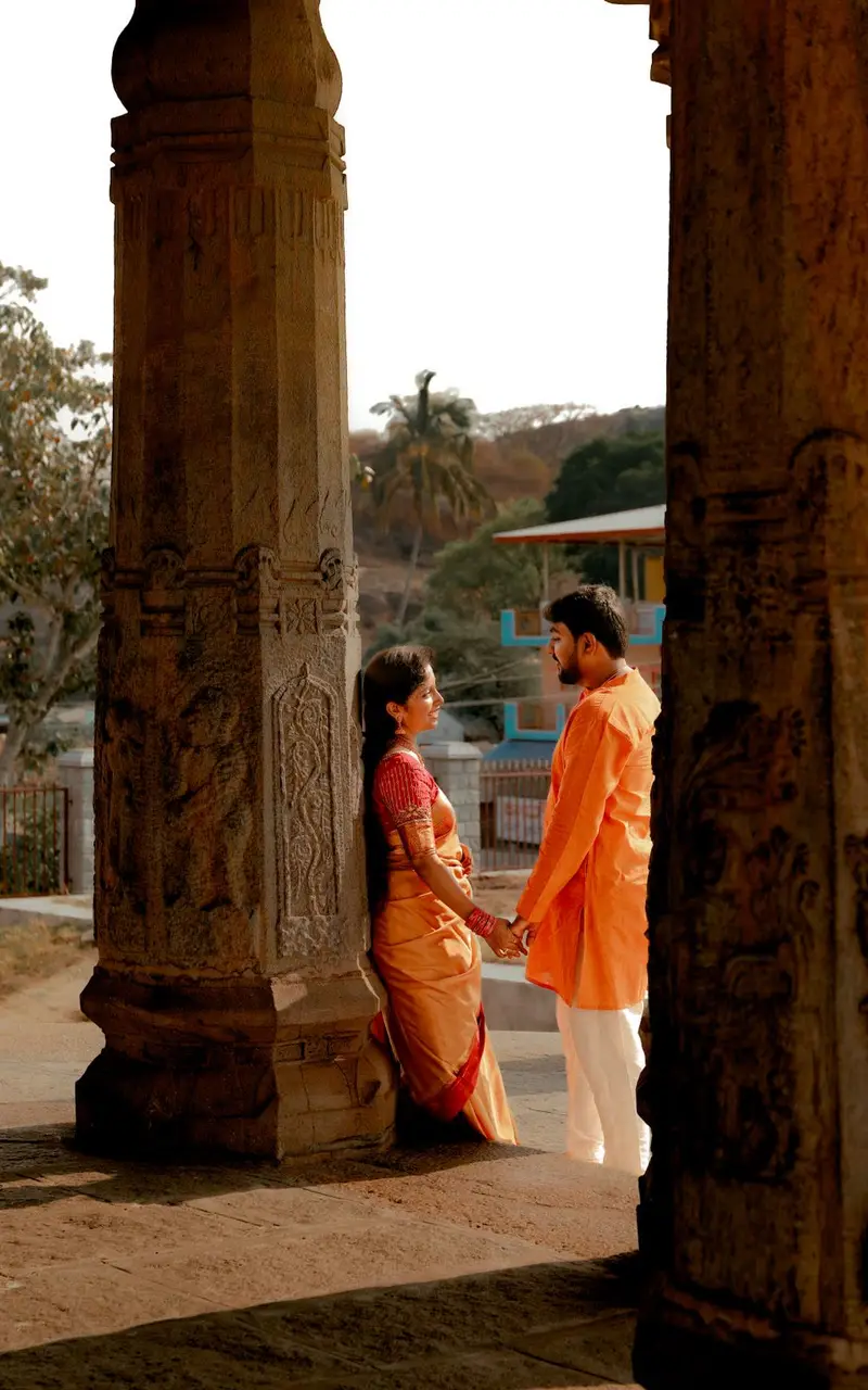 A couple between tall stone columns, in warm light.