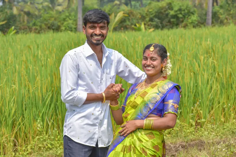 A couple in traditional dress in a green paddy field.