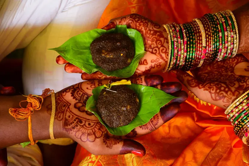 Hands holding the jeelakarra-bellam paste on betel leaves.