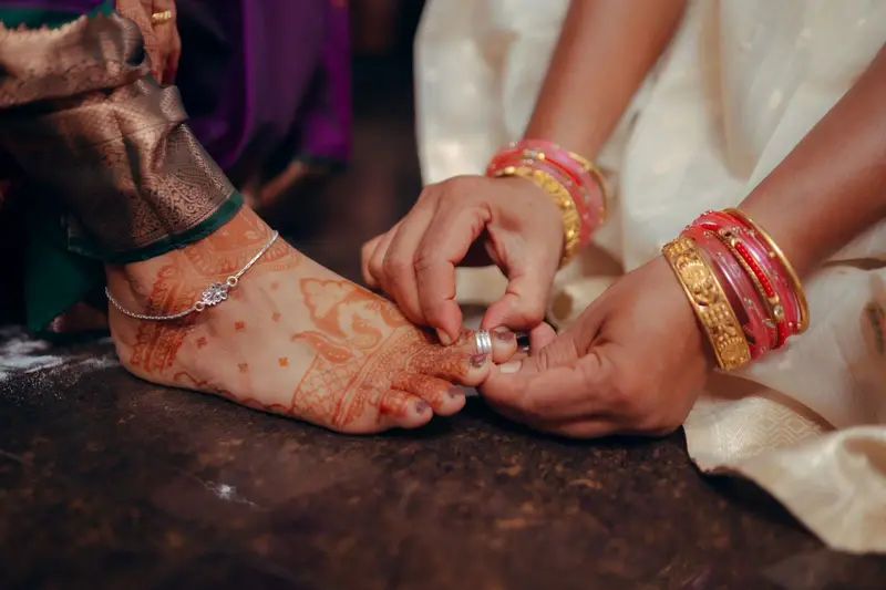 The groom placing mettelu (toe rings) on the bride's foot.